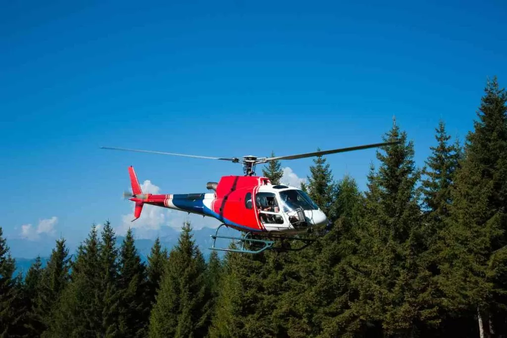 Bright red helicopter over the trees in Lake Tahoe.